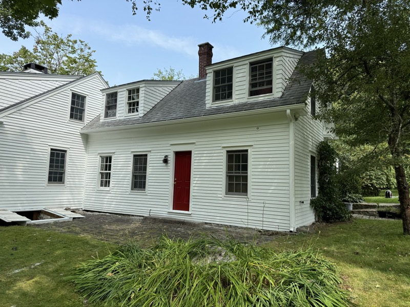 White farmhouse with a red door after an exterior repaint