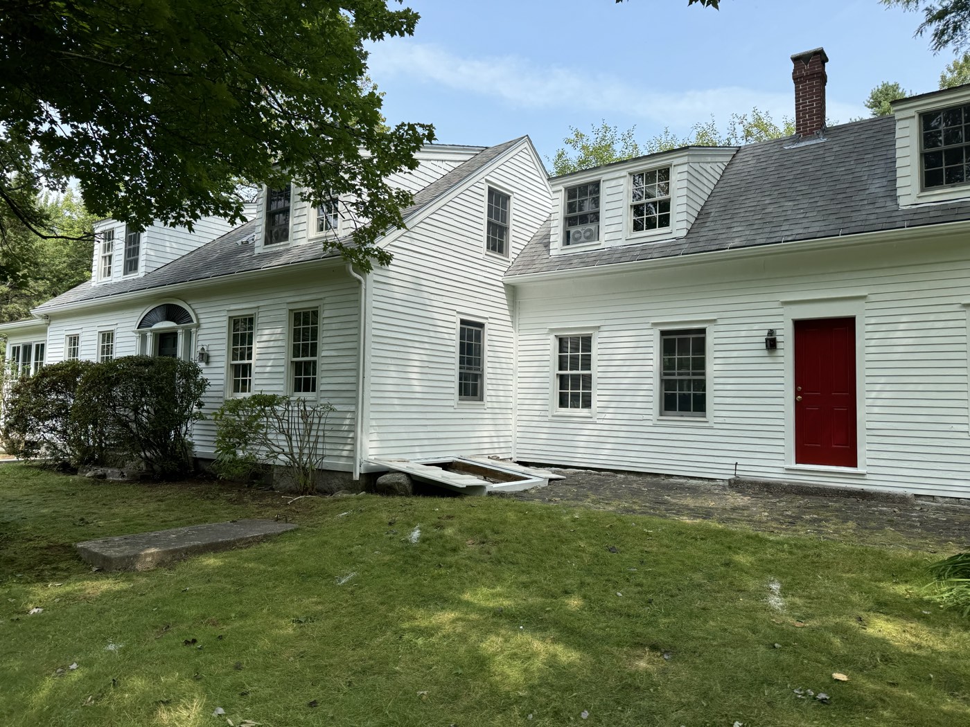 Freshly painted white clapboard siding, trim and red front door