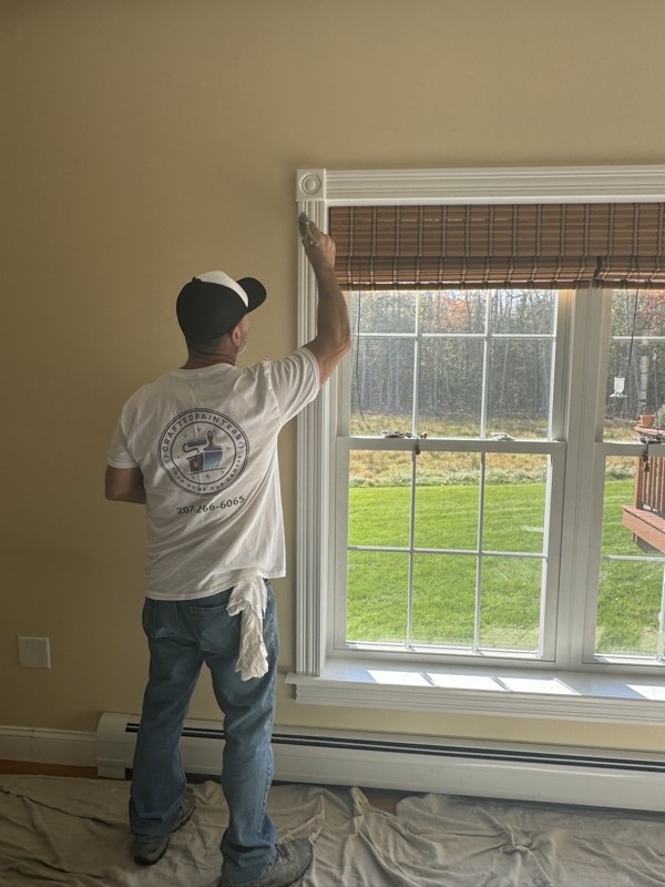 Painter cutting in trim around a large window