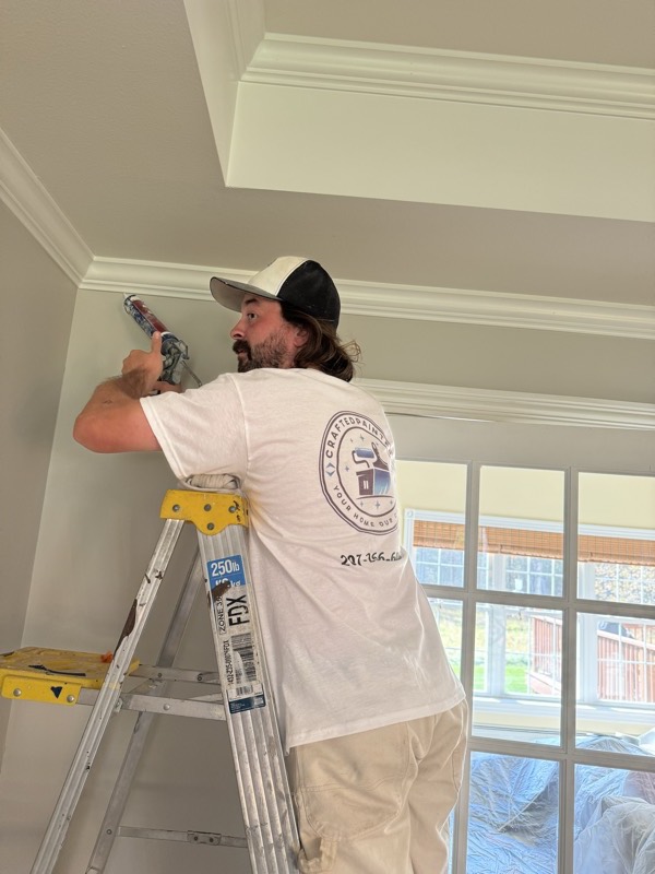 Painter cutting in the ceiling line from a stepladder