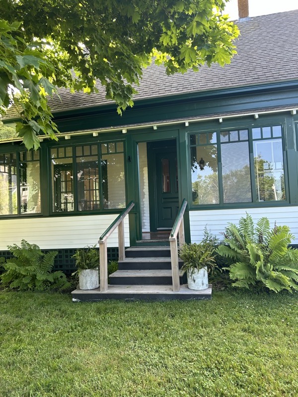 Porch entrance with dark green trim and screened windows