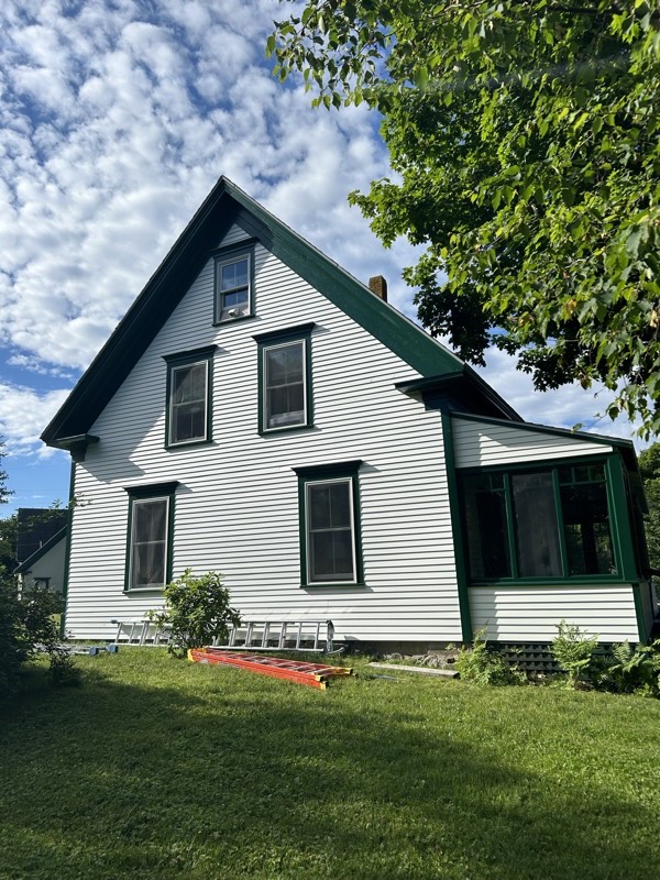 White house with dark green trim and a screened porch