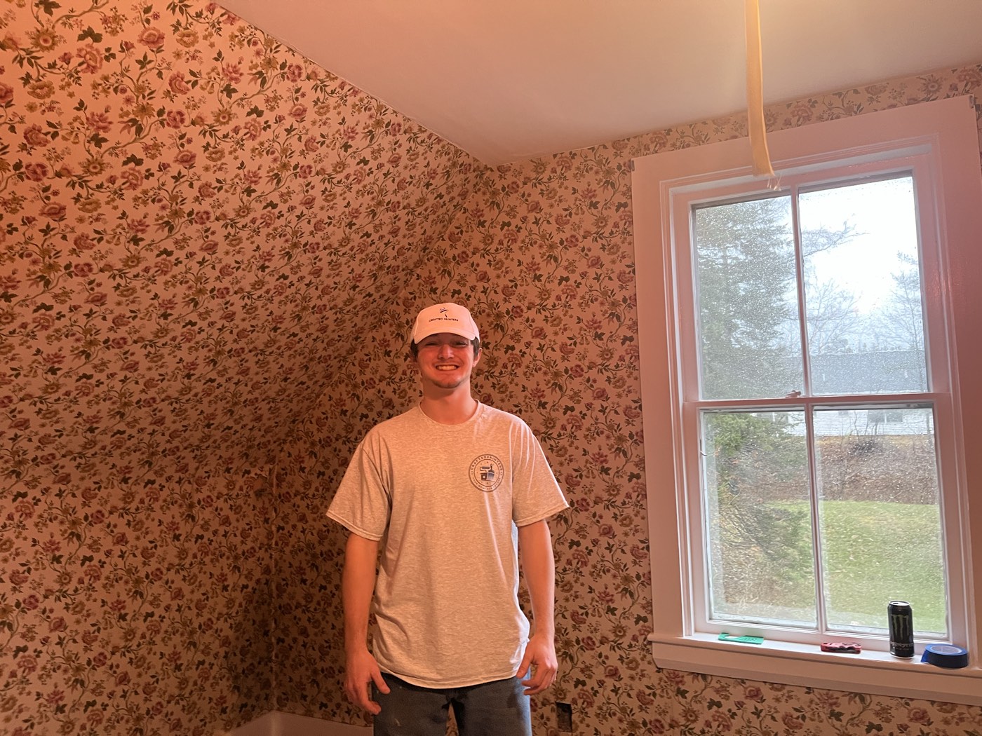 Crew member in a bedroom covered in dated floral wallpaper, with the floor protected, ready for removal