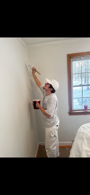 Painter cutting in a repaired wall beside a window