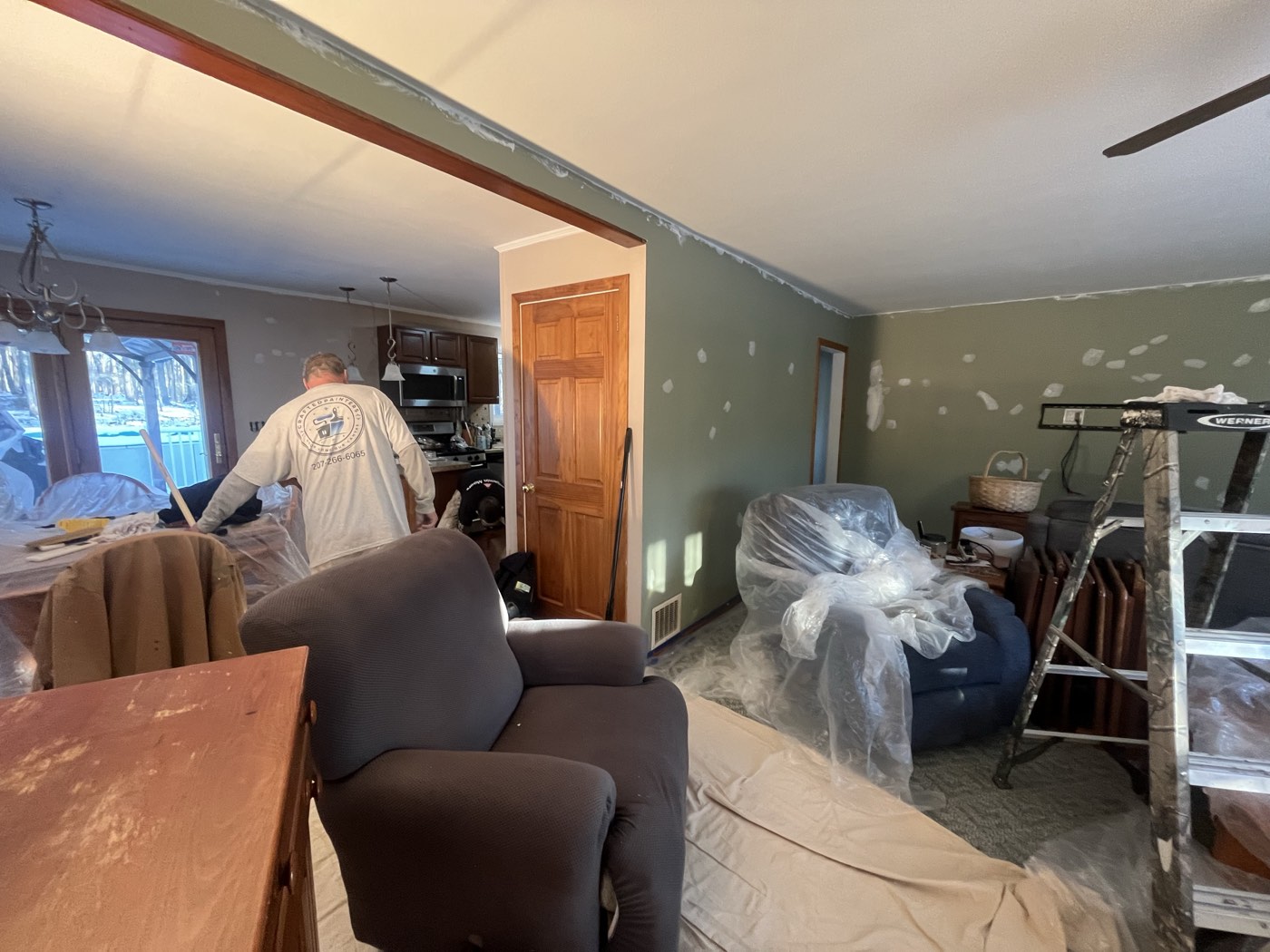 Patched walls ready for sanding and paint, with furniture wrapped and floors protected