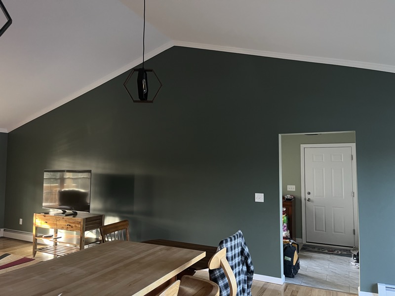 Room with a freshly painted deep green accent wall under a vaulted ceiling