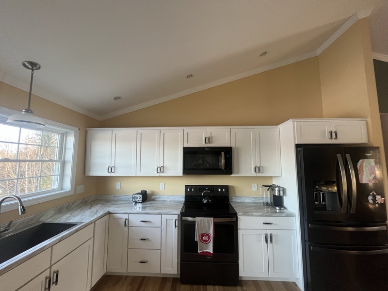 Kitchen with white painted cabinets under a vaulted ceiling