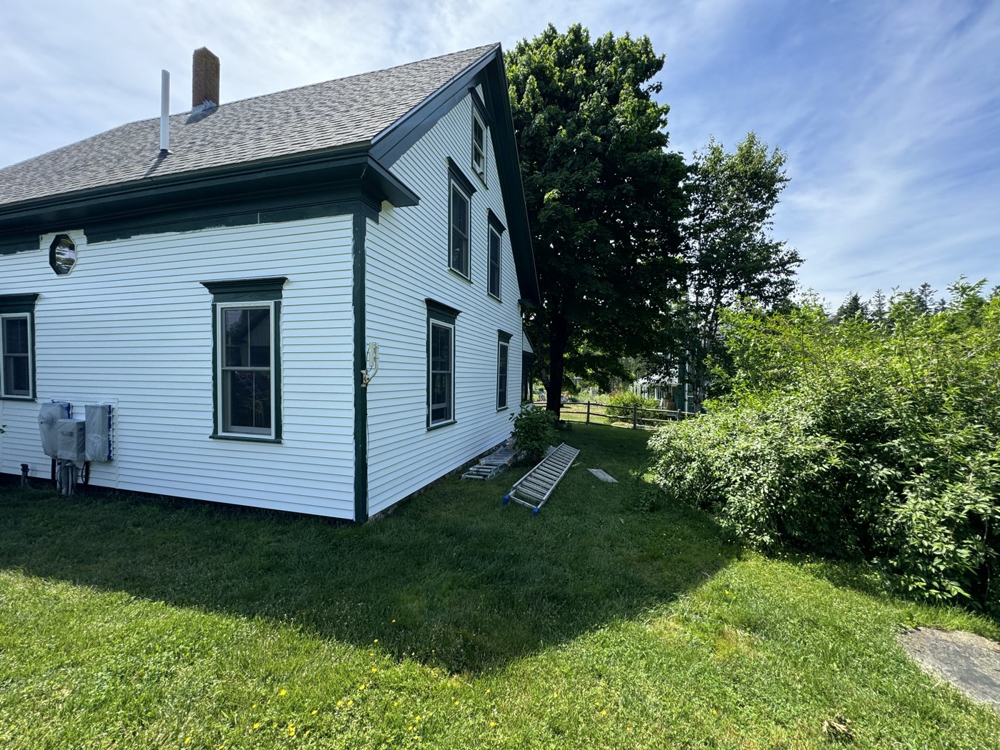 White house with dark green trim after a full exterior repaint