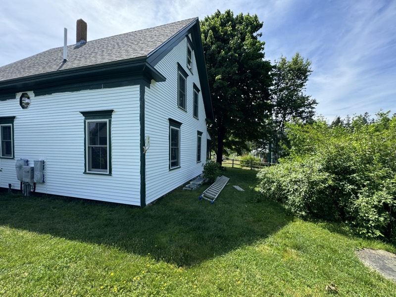 White house with dark green trim after a full exterior repaint